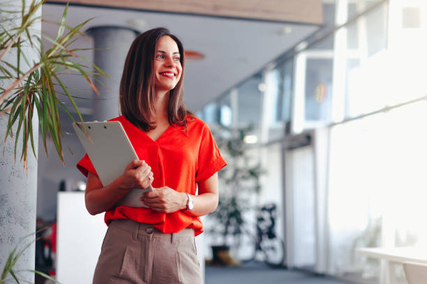 istock Smiling businesswoman standing in office with clipboard 2174203549