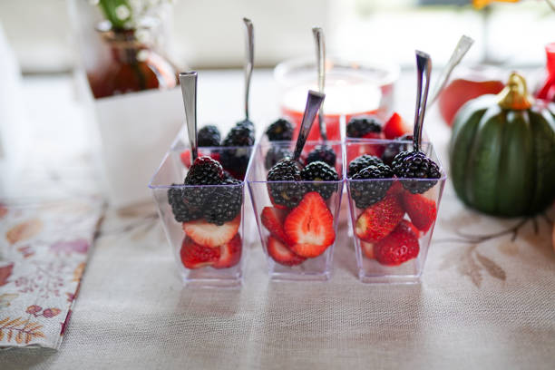 istock cups filled with fresh strawberries and blackberries, arranged on a festive table decorated with a small pumpkin, flowers, and candles 2174204277