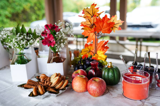 a beautifully arranged autumn-themed table setting with apples, cookies, a candle, flowers, and decorative leaves