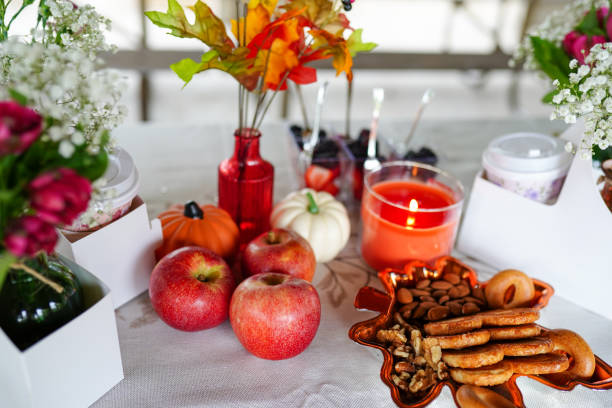 istock a cozy autumn-themed table setting with apples, pumpkins, snacks, and a lit candle, surrounded by decorative flowers and fall leaves 2174204879