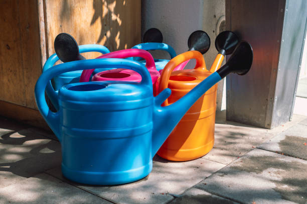 istock Brightly colored plastic watering cans (blue, pink, orange) stacked together in sunlight on a patio 2174205199