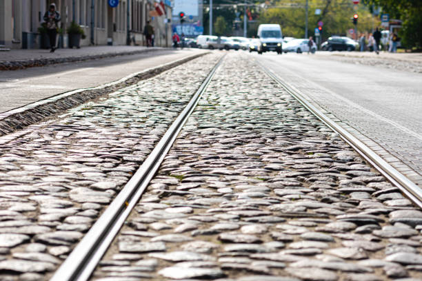 Tram tracks run along a cobblestone street glistening in the sunlight.