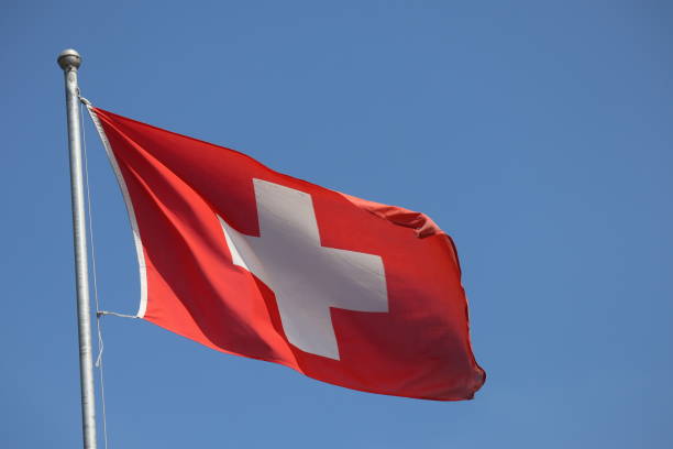 istock Swiss flag flying in the wind against blue sky 2174219843