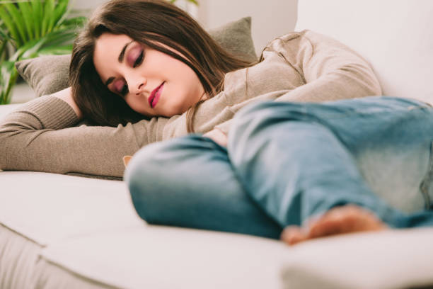 istock Young woman sleeping peacefully on sofa at home 2174220698