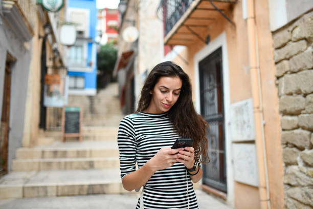 istock Young female looking at map directions on smartphone while sightseeing Alicante, Spain 2174223183