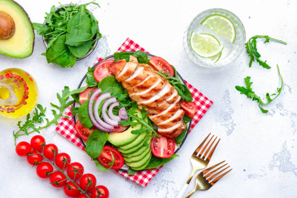 istock Grilled chicken fillet with avocado, spinach and tomato garnish, white background, top view 2174224397