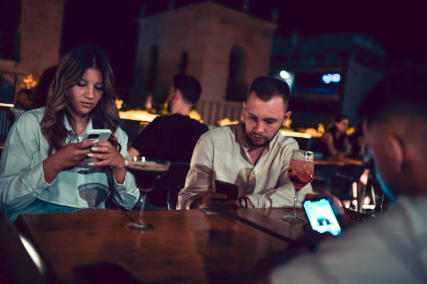 istock Friends using smartphones while relaxing in cocktail bar at night 2174229770