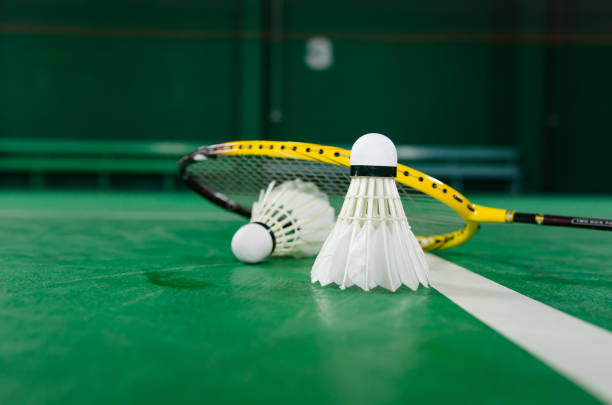 istock Badminton rackets and white cream badminton shuttlecocks after playing or after games on green floor in indoor badminton court soft focus concept for badminton lovers around the world. 2174230202