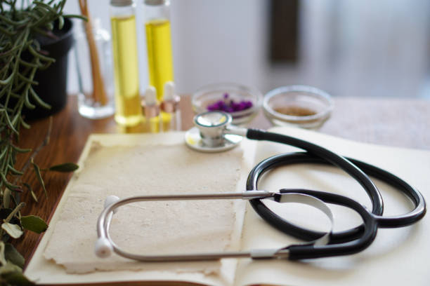 istock open book on a homeopath's table with stethoscope, herbs and oils 2174233830