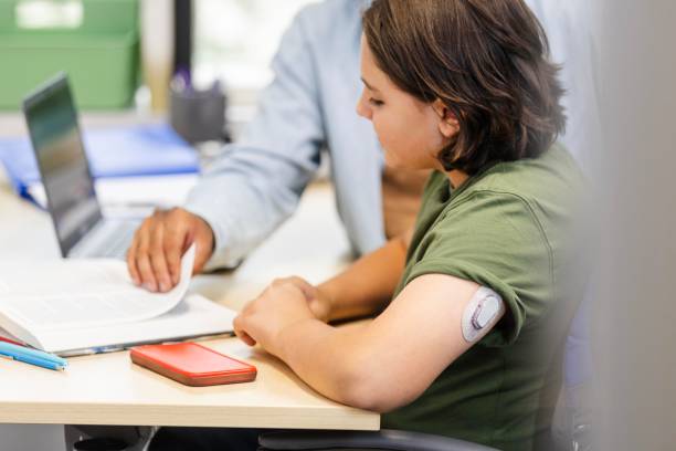 istock Boy with glucose monitor keeps phone close by during school 2174234970