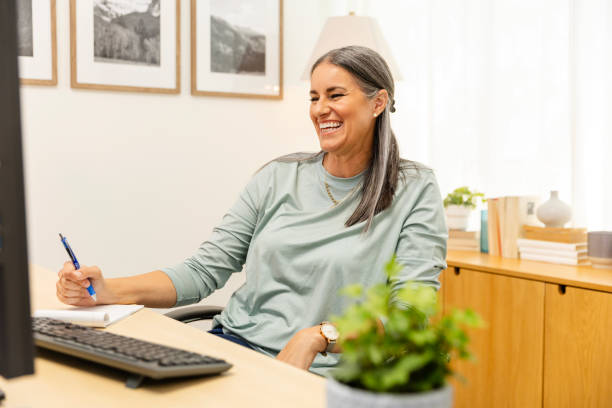 istock Non-traditional female student takes notes during online class 2174235153