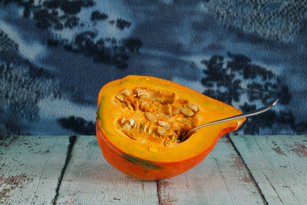 A halved pumpkin in front of a rustic background.