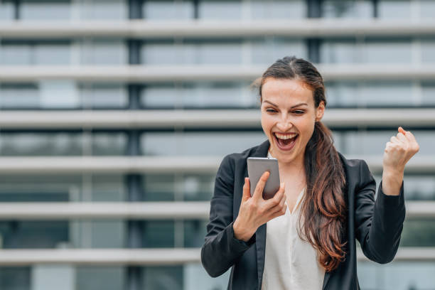 istock business woman looking at mobile phone with successful expression 2174245509
