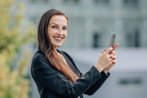 istock business woman with mobile phone outdoors, smiling 2174245568