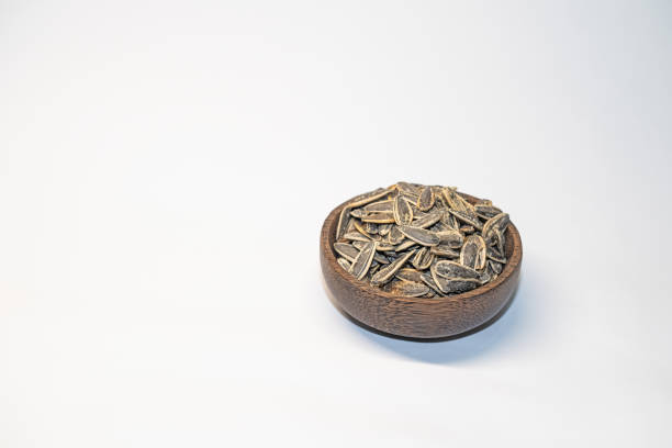 Roasted, salted sunflower seeds in a bowl on a white background.