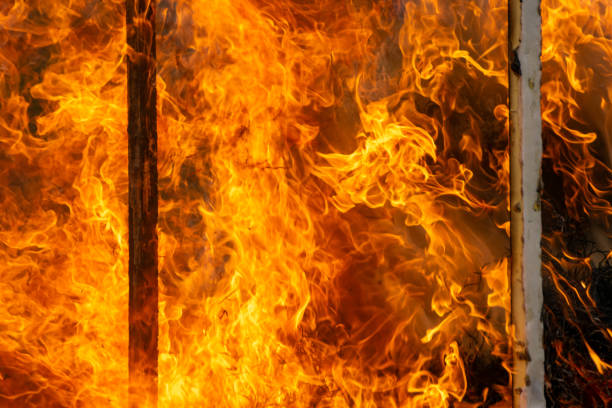 flames from a fire, a burning wooden structure. Burning orange hot sparks fly from large fire