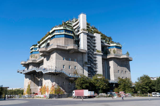 A former World War II anti-aircraft bunker in St. Pauli, Hamburg, repurposed into a modern, eco-friendly structure. The Brutalist building is adorned with green rooftop terraces, blending history and sustainability in an urban landscape.