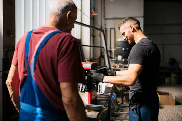 istock Young man using hydraulic aluminium punching machine with senior man watching 2174260360