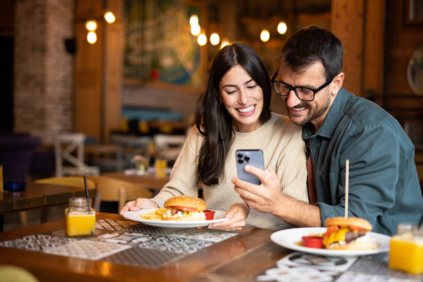istock Happy couple in restaurant looking at phone 2174260805