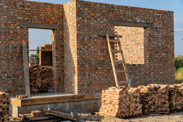 istock Construction workers are building a brick wall, which stands partially completed. A wooden ladder leans against the structure, and neatly stacked bricks nearby await use 2174262751