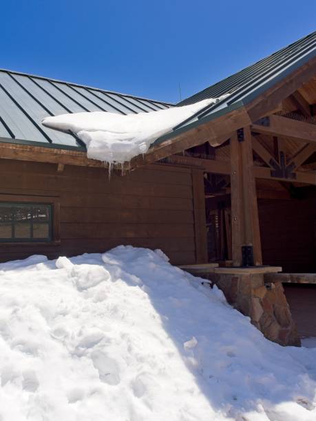 A closeup of icicles hanging from a wooden roof surrounded by hills in winter in the countryside