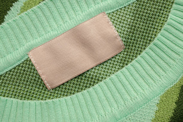 istock Brown blank laundry care clothes label on green shirt fabric background 2174277880