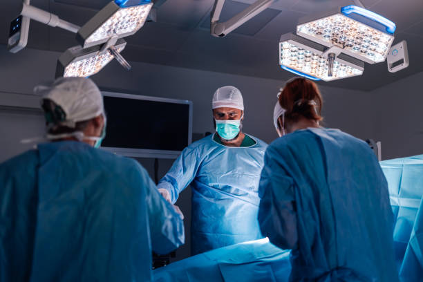 istock Team of surgeons working precisely under operating room lights. 2174278931