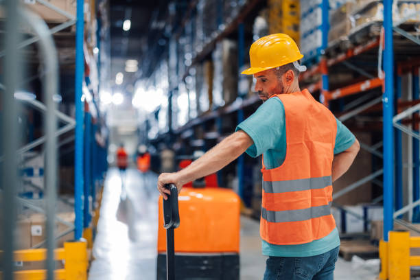 istock Warehouse employee using pallet jack to move goods, in a safe manner. 2174279039