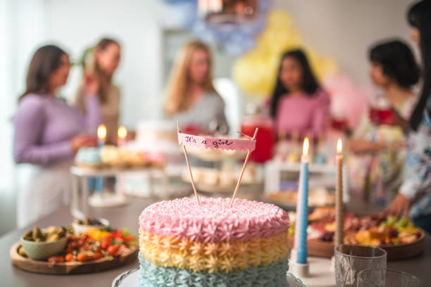 Beautiful colorful and delicious cake at a baby shower celebration displayed on a tray with diverse females in the background.