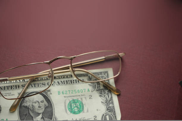 One dollar bill and glasses on dark red background. Financial concept