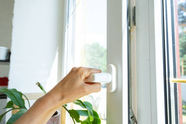 istock The hand holds the handle of a plastic double-glazed window, closing and opening the window with a rotary mechanism, the position of the handle for ventilation, micro-ventilation 2174287561