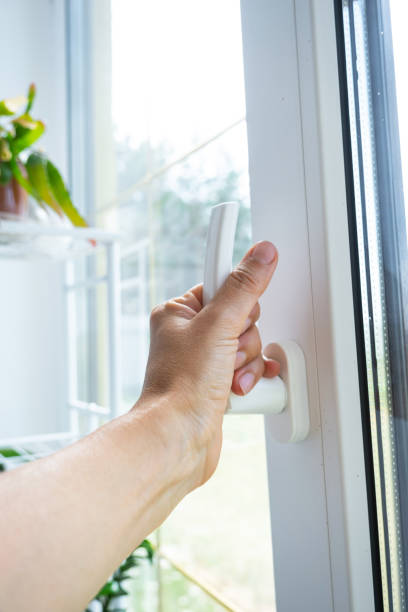 istock The hand holds the handle of a plastic double-glazed window, closing and opening the window with a rotary mechanism, the position of the handle for ventilation, micro-ventilation 2174287606