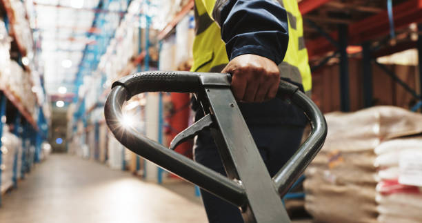 istock Warehouse, hand and worker pull pallet truck for supply chain, restock or moving freight. Factory, person and trolley for cargo storage, distribution logistics and back in shipping industry closeup 2174296615