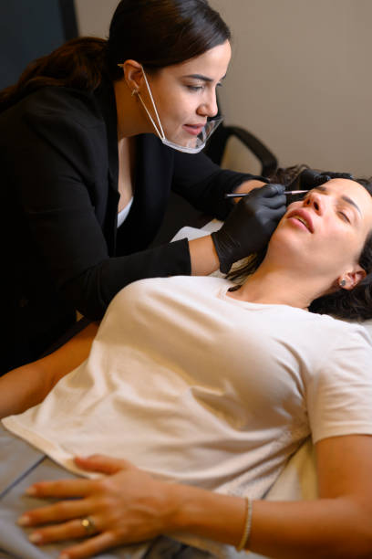 istock Beautician applying permanent eyebrow makeup on woman 2174299408