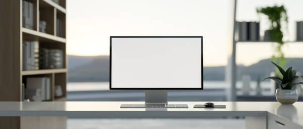 istock A computer on a white desk in a modern office, featuring a large window with a nature view. 2174299590
