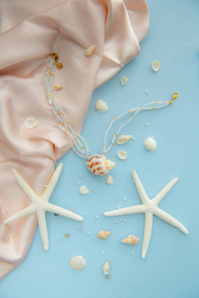istock Pendant necklace made of a seashell and white beads surrounded by small seashells, starfish, pearls 2174301156