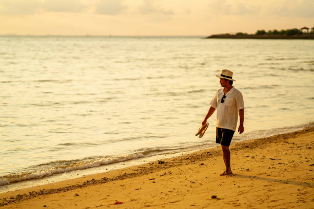 Mid adult man walking along the beach during sunset