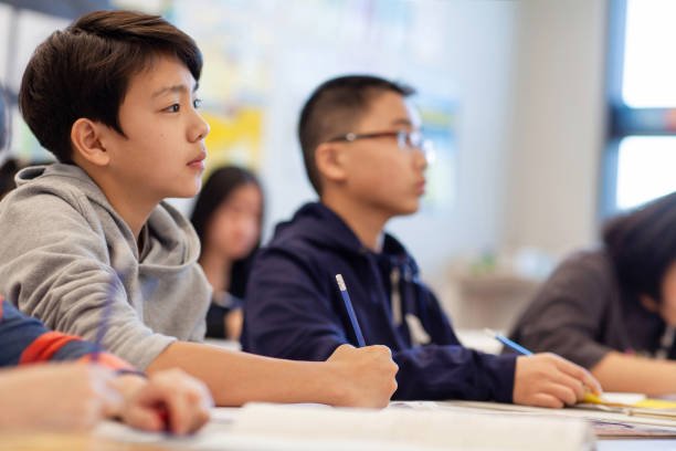 istock Asian multiracial Korean Japanese boy studies in elementary school classroom with classmates 2174309830