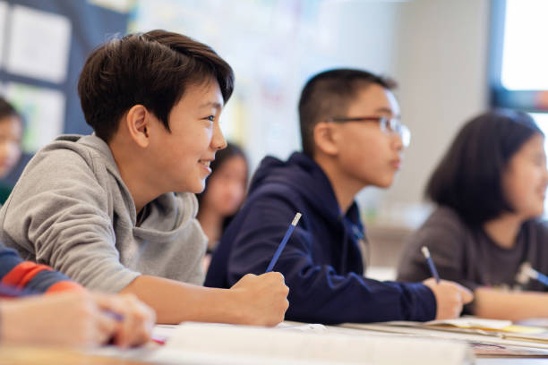 istock Asian multiracial Korean Japanese boy studies smiling in elementary school classroom with classmates 2174310002