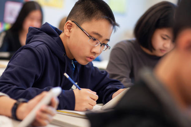 istock Asian Chinese boy studies in elementary school classroom with classmates 2174310049