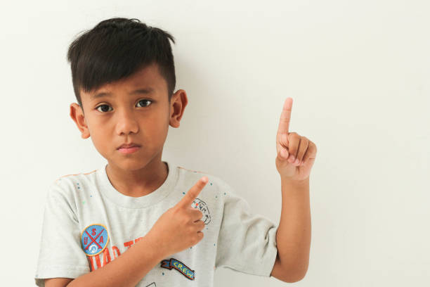 istock asian boy isolated on white background pointing finger up. 2174311393