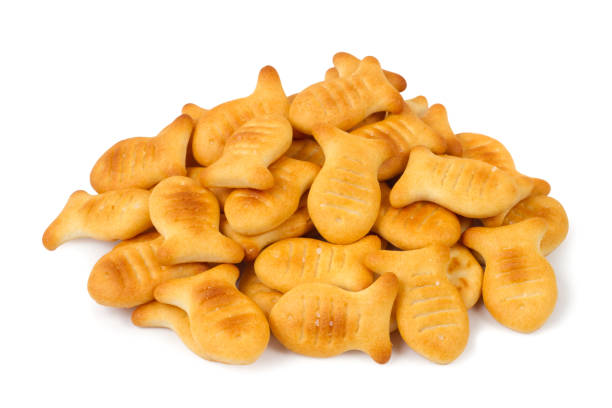 A pile of fish-shaped cookies isolated on a white background. A pile of fish-shaped cookies isolated on a white background. Lots of fresh, crispy cookies. goldfish snack stock pictures, royalty-free photos & images