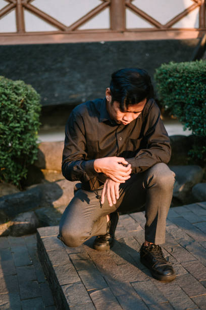 istock Southeast Asian man squatting while checking his watch, appearing thoughtful or in a hurry. 2174315893