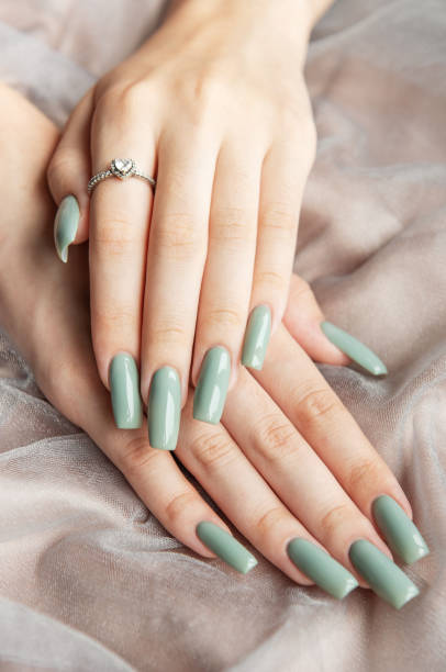 istock Elegant hands with long green nails resting on soft fabric 2174320360