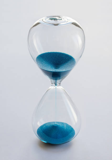 istock Hourglass containing blue sand isolated on white background 2174325817