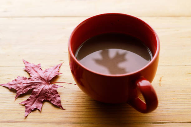 istock Cup of delicious hot chocolate with red maple leaf reflection on wooden table background. Selective focus. 2174327509