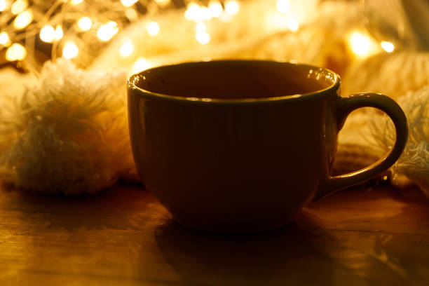 Cup of delicious hot chocolate under warm light on wooden table background. Selective focus.