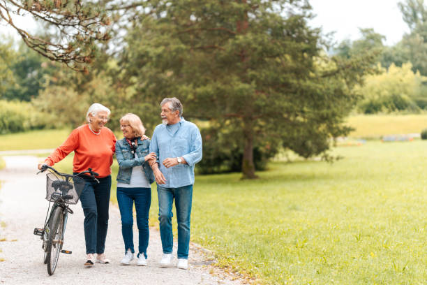 istock Senior Friends Enjoying Park Stroll with Bicycle 2174331141