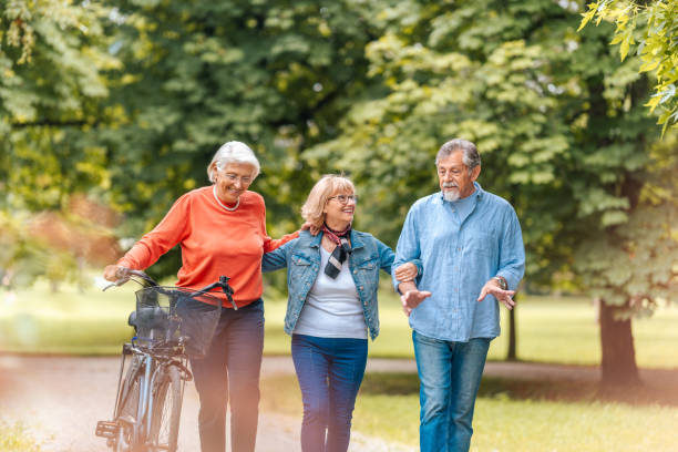 istock Senior Friends Enjoying Park Stroll with Bicycle 2174331150