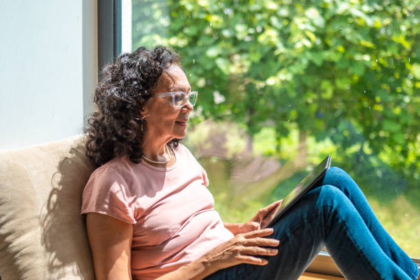 istock Senior Hispanic Woman Enjoying Tablet Time by Window 2174331510